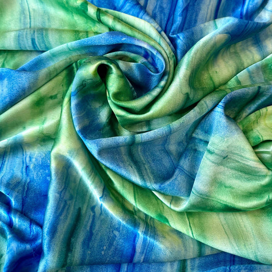 Tissu en satin imprimé "étreinte minérale" vert et bleu de la marque Tiss'ART, motif élégant et coloré visible sur l'image.
